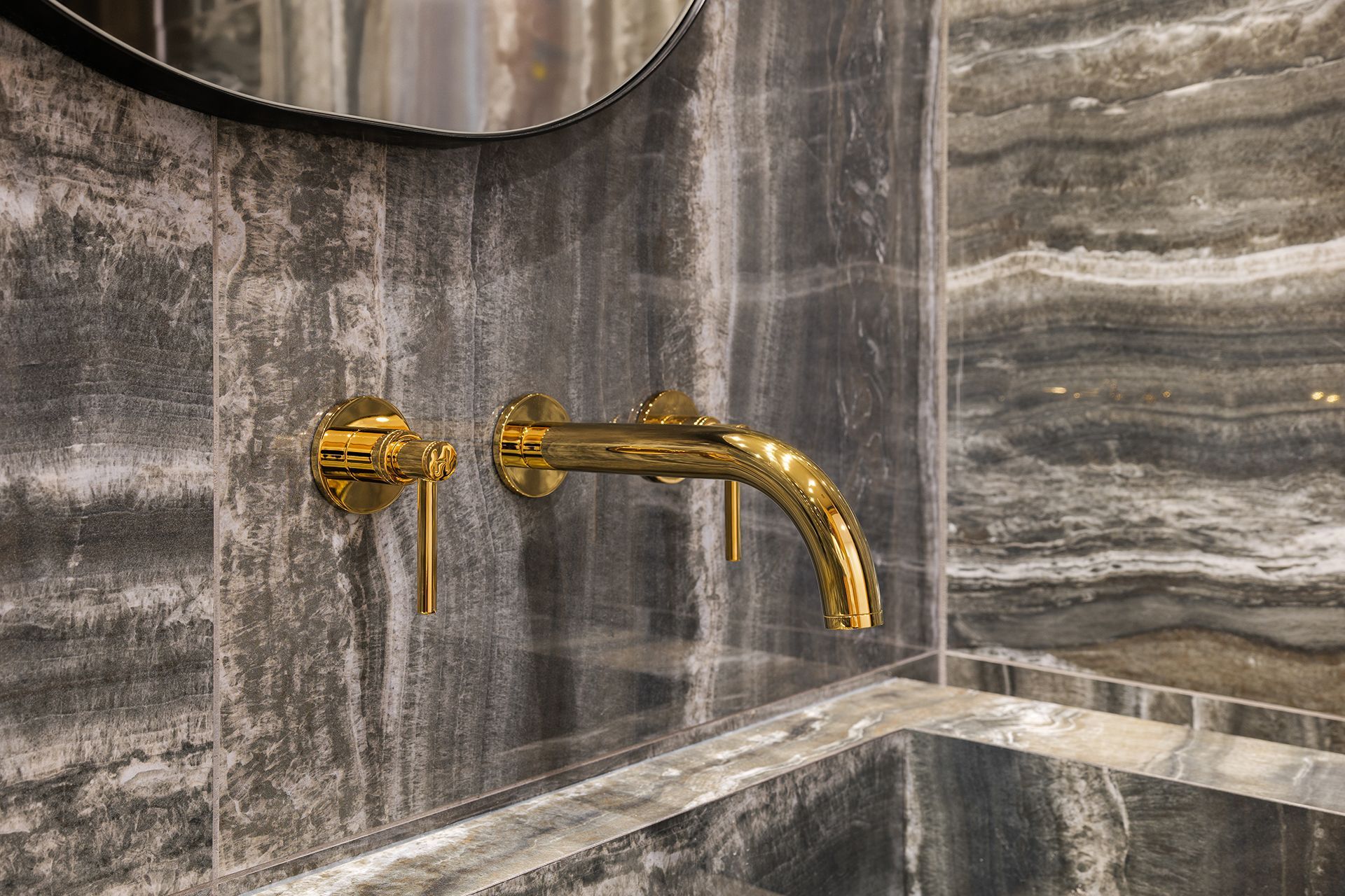 a bathroom sink with a gold faucet and a mirror