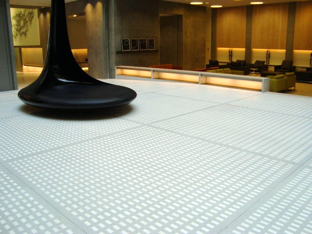 A black tiling equipment sits on a white tiled floor in a room.