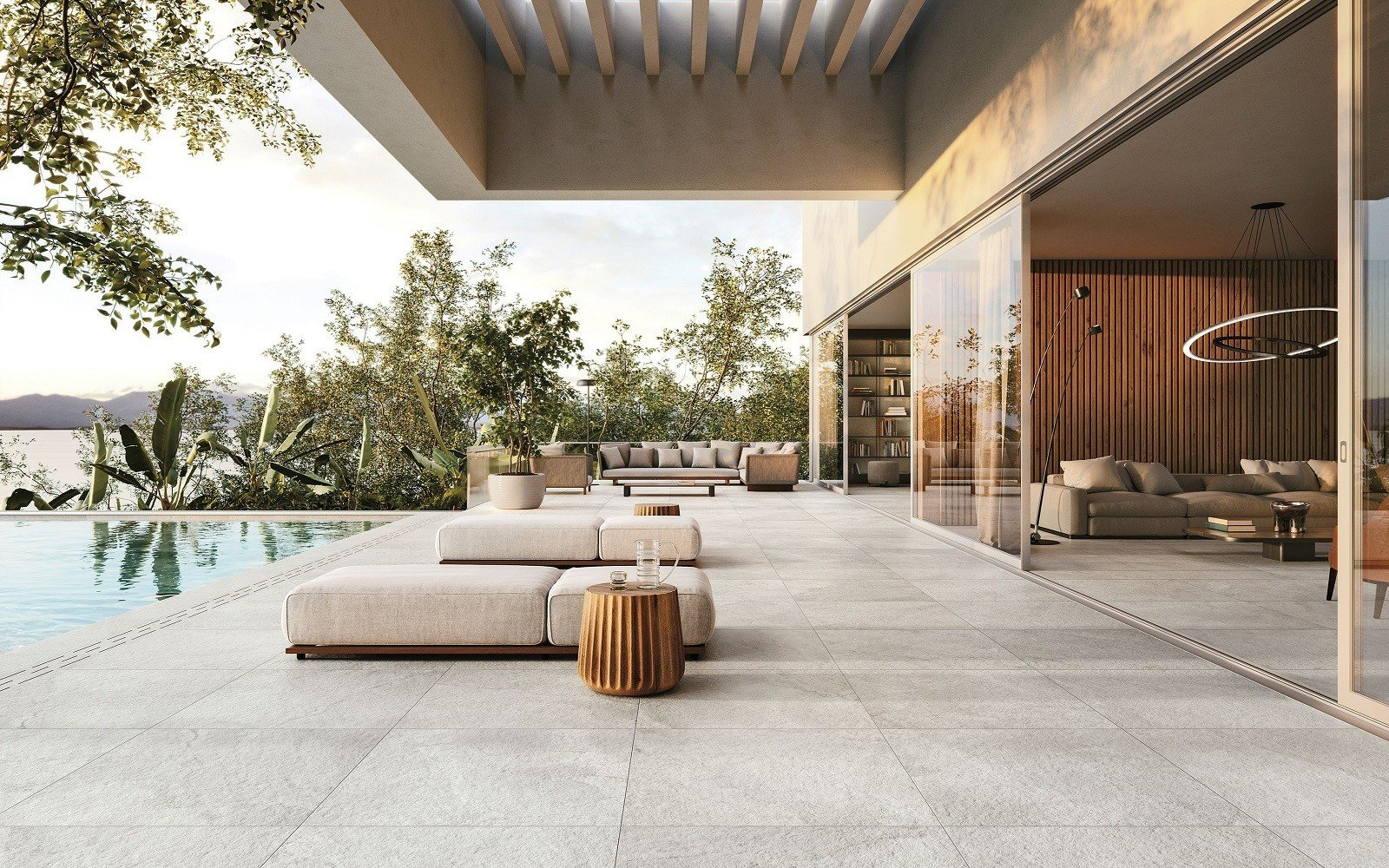 Patio with pool overlooking a lake; modern furniture; neutral colors, glass sliding doors; lush greenery.