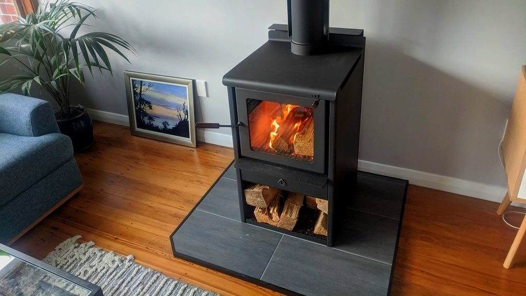 A wood stove is sitting in a living room next to a couch.