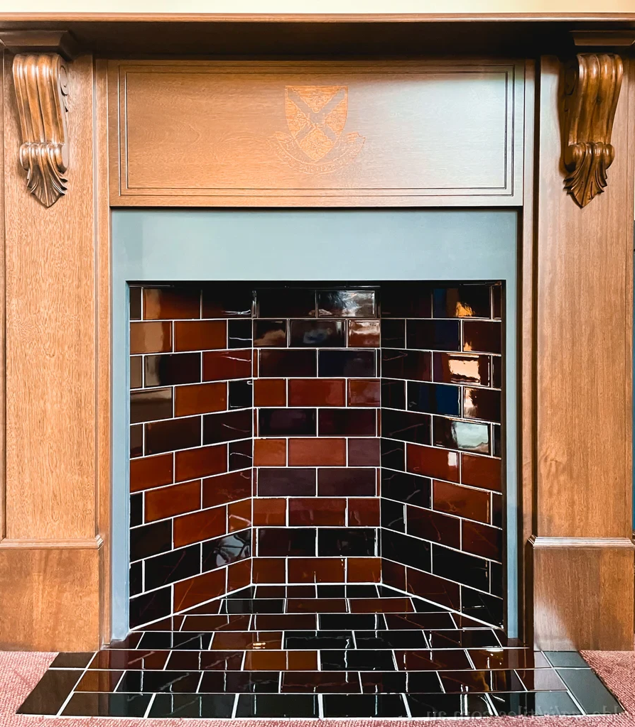 A fireplace with brick tiles and a wooden mantle.