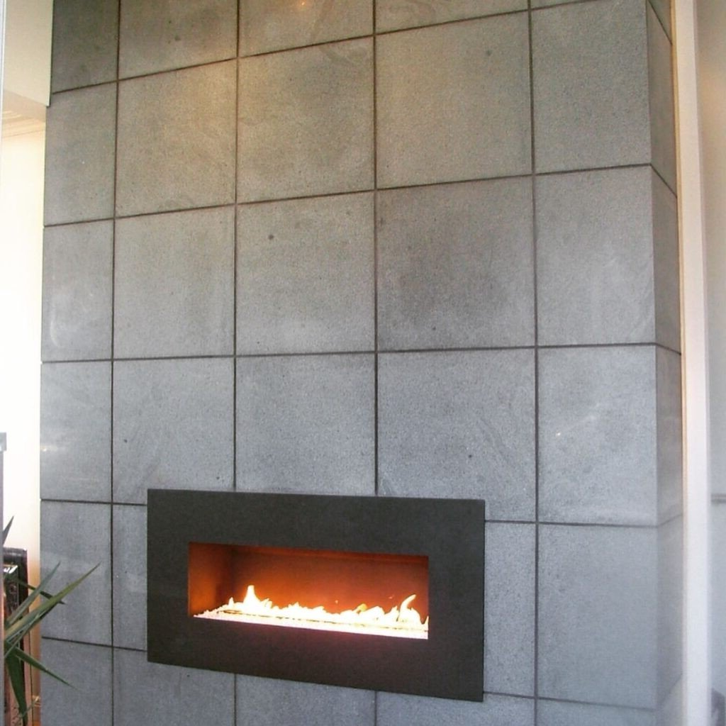 A fireplace is built into a gray tiled wall.