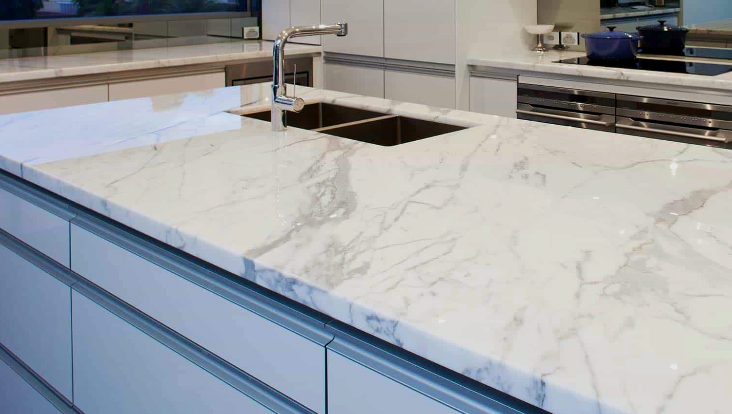 Granite countertop island with sink and silver faucet in modern kitchen.