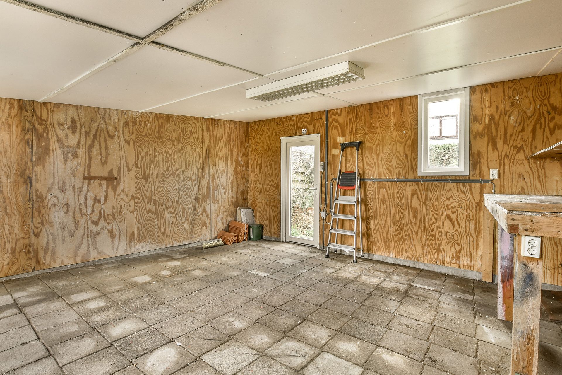 A room in midst of being renovated, with no tiles yet on the floor and half painted walls.