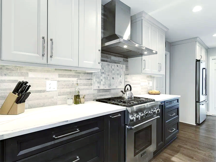 A kitchen with stainless steel appliances, black cabinets, white counter tops, and a stove top oven.