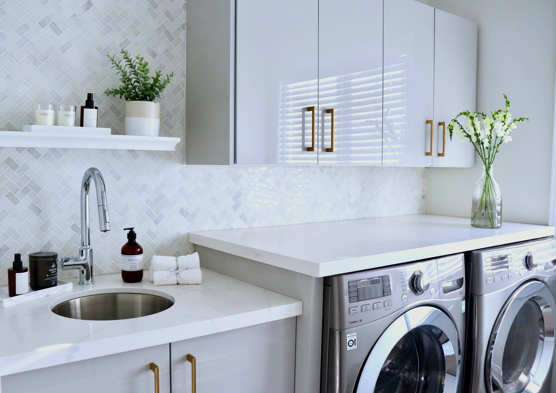 A laundry room with a washer and dryer, sink, and cabinets.