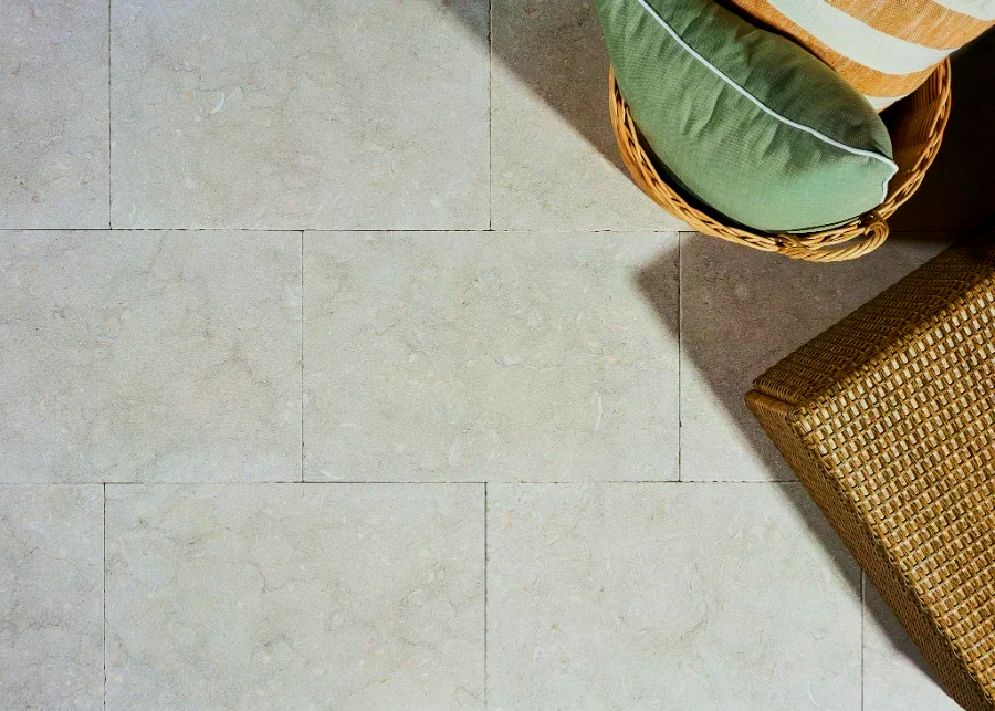 Light stone tile floor with a basket holding green and striped pillows.