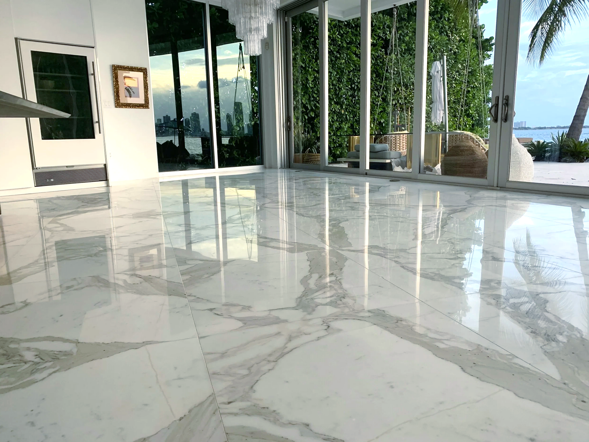 A large lounge area with marble flooring overlooking the ocean.