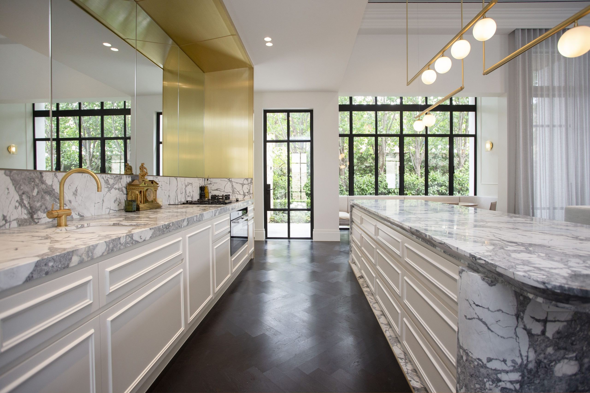 Elegant kitchen with marble countertops, gold accents, and large windows.