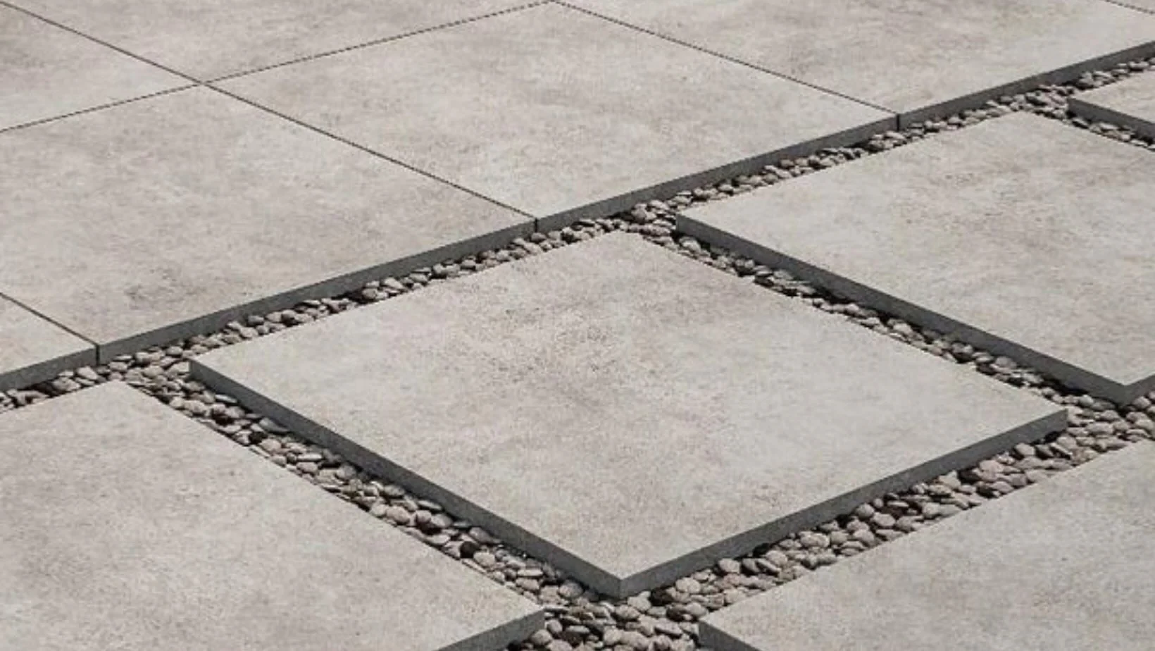 A close up of a patio with square tiles and gravel.