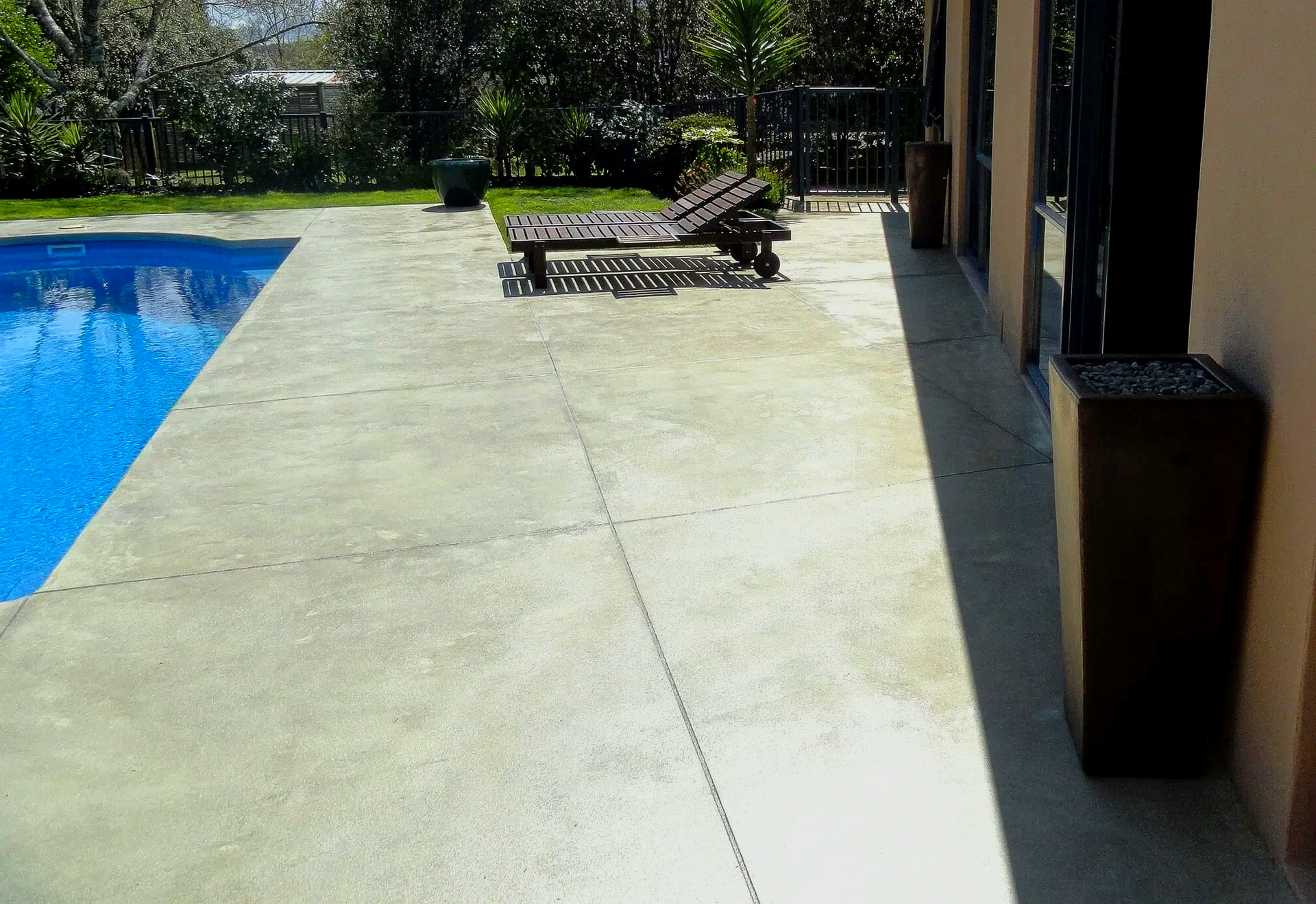 A patio with chairs and a swimming pool in the background.