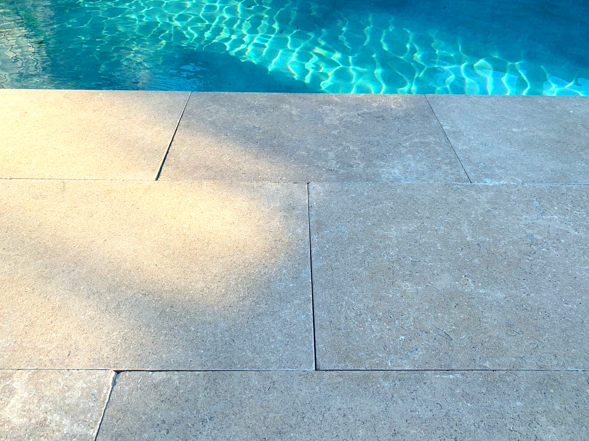 A swimming pool is reflected in the tiles on the side of the pool.