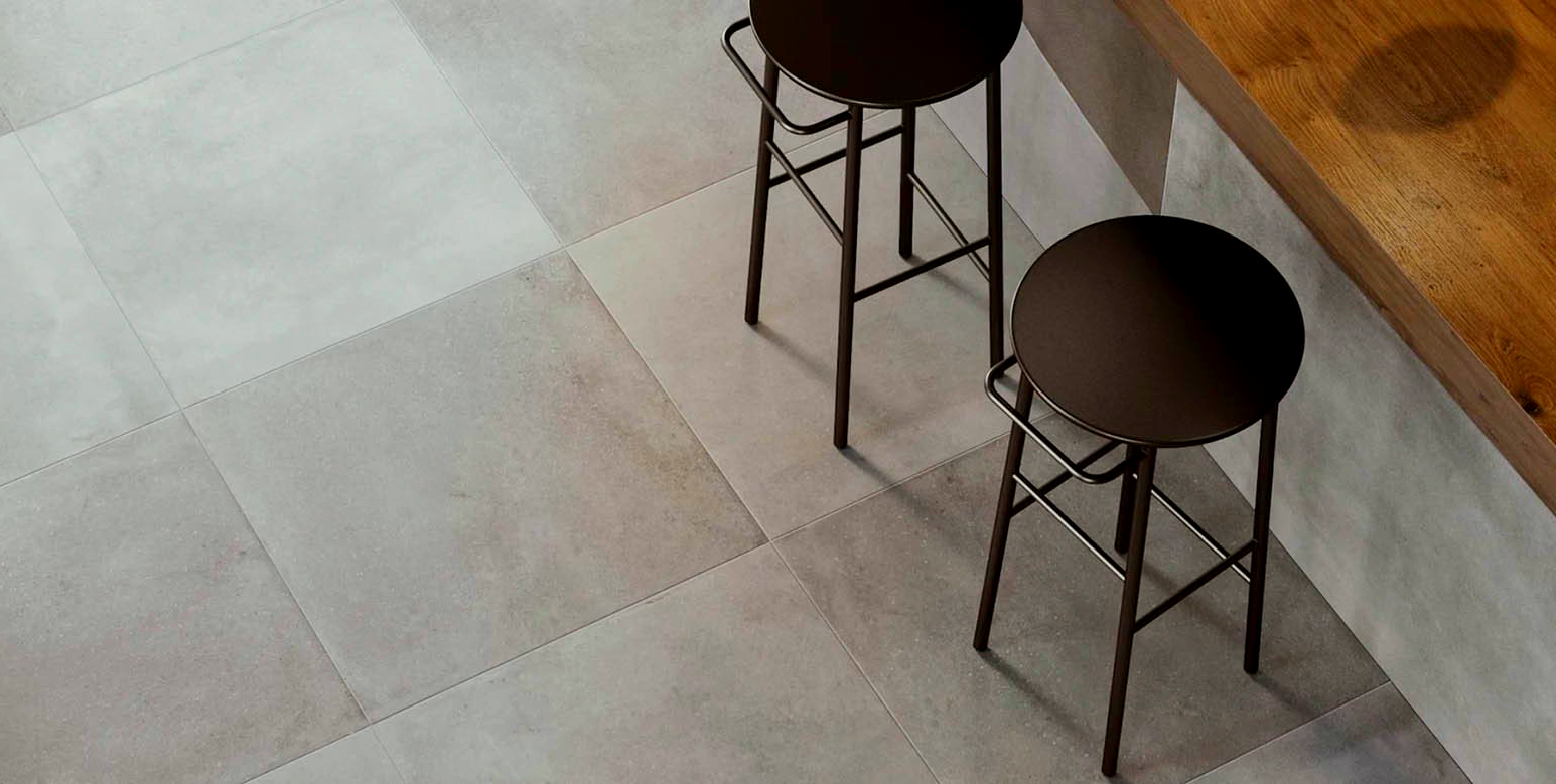 Two brown bar stools at a wooden counter on a light gray tiled floor.