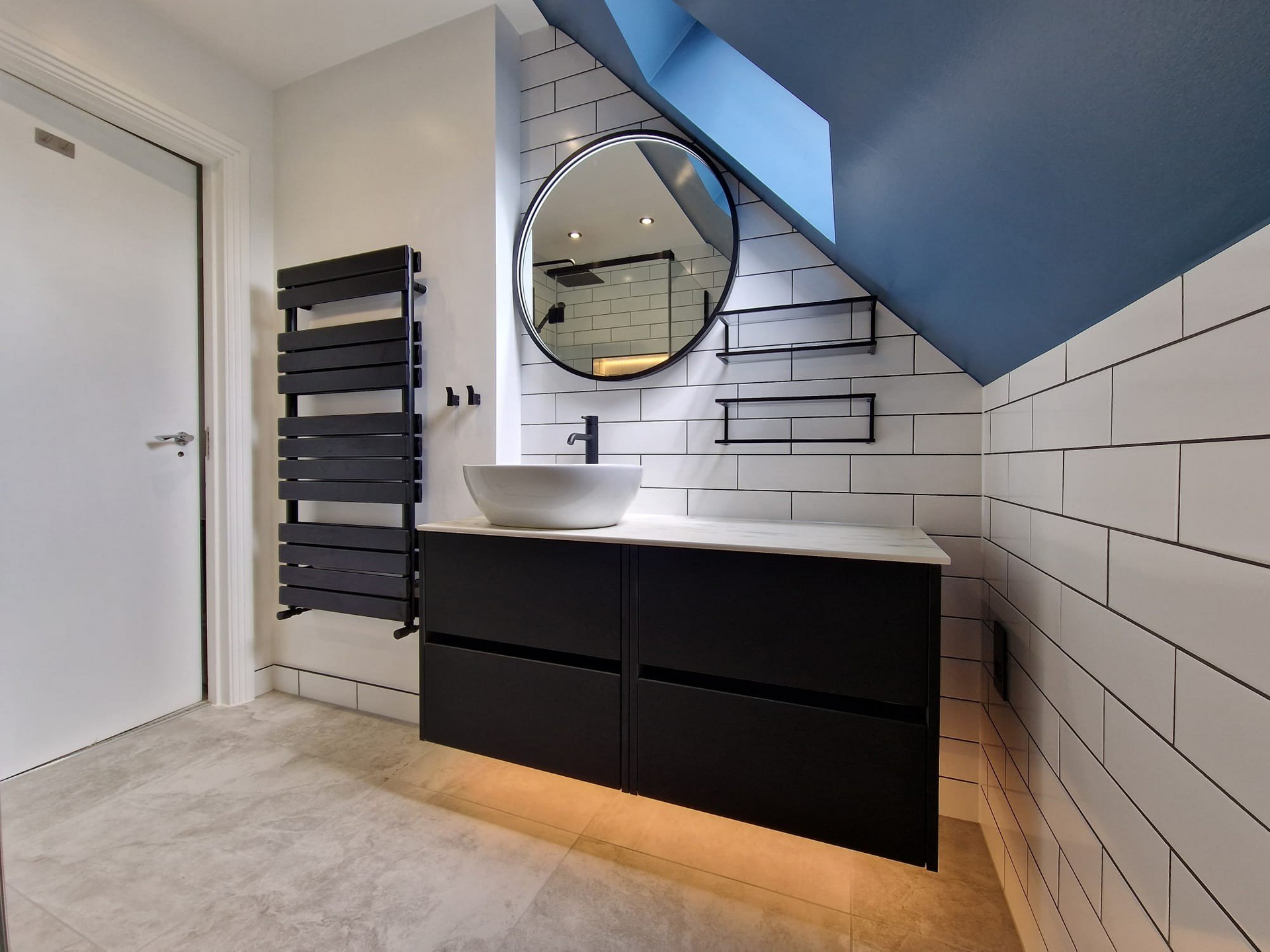 A bathroom with a sink and a round mirror.