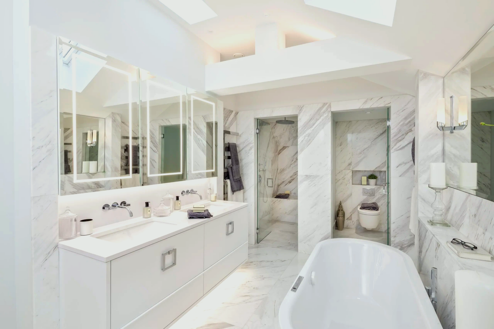 A bathroom with a tub, sinks, mirrors and a skylight.