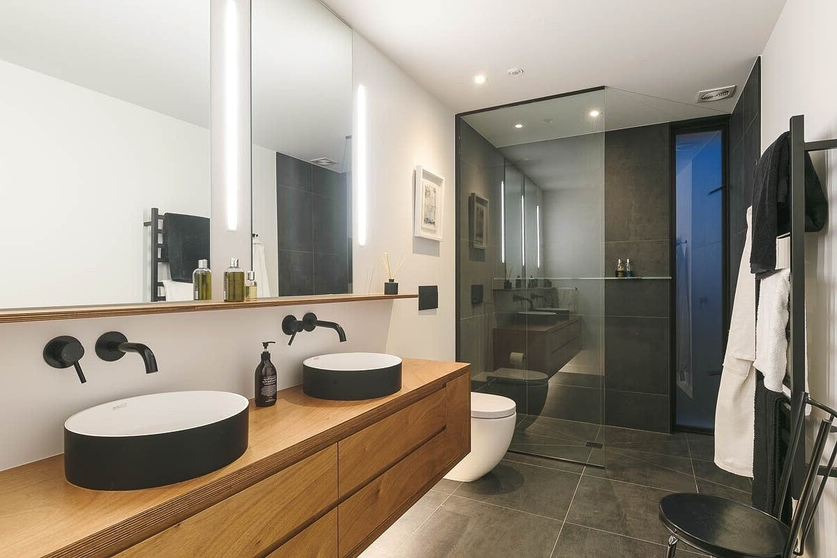 A bathroom with two sinks, a toilet, and a walk in shower.