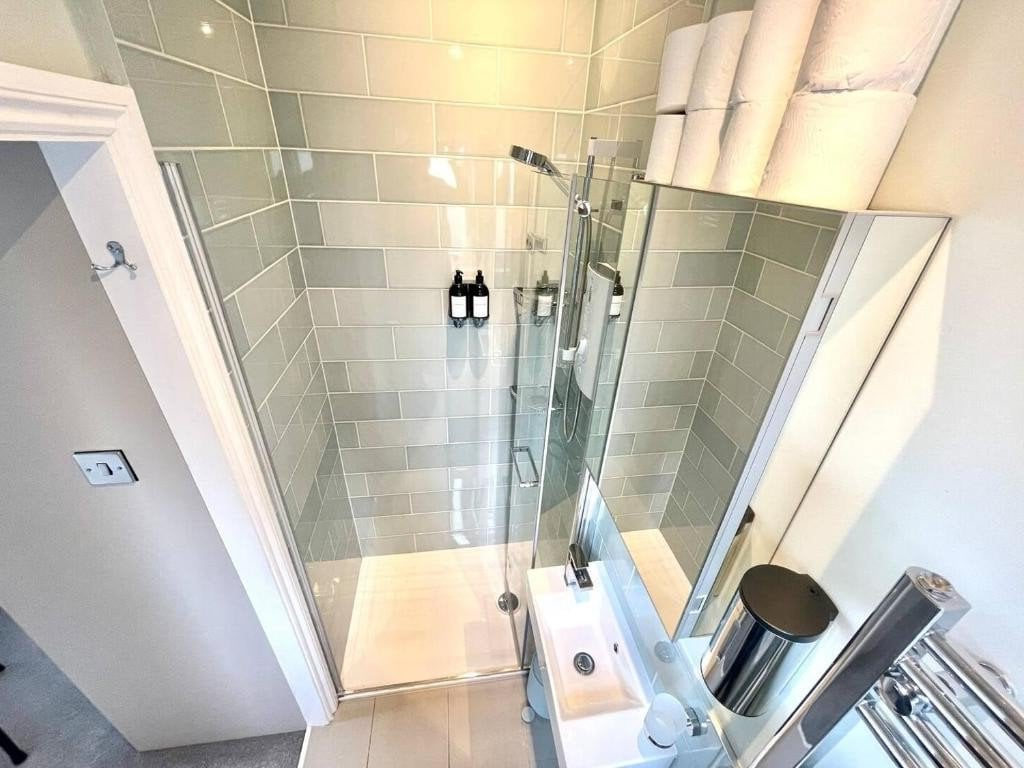 A bathroom with a shower, sink and mirror.