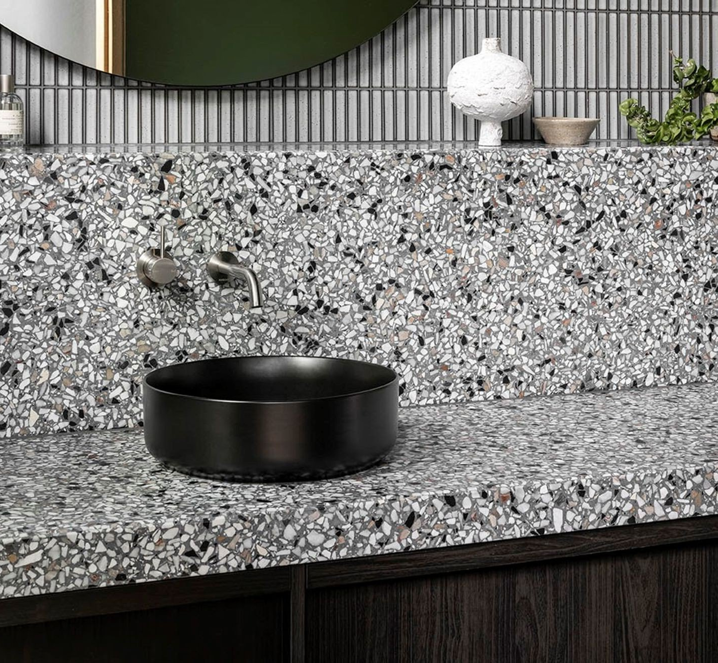 Bathroom with terrazzo countertop, black vessel sink, and vertical tile backsplash.