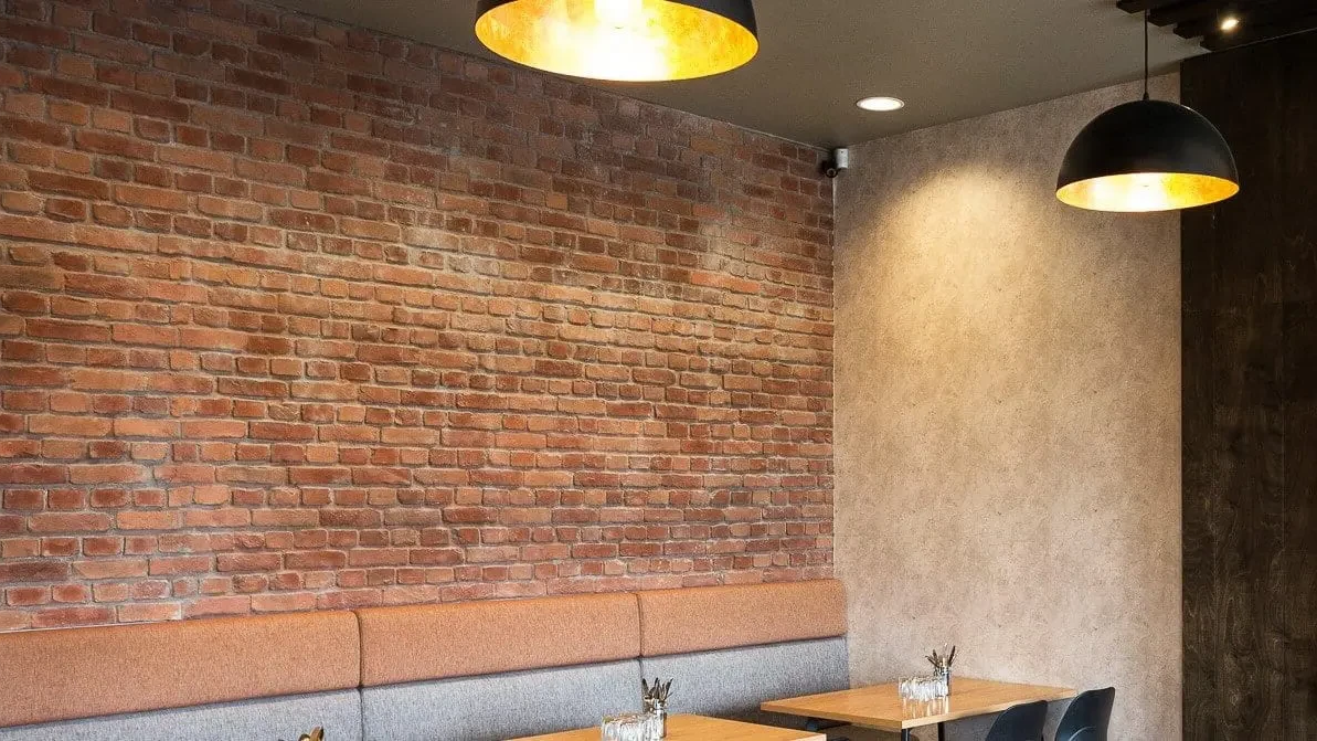 A restaurant with tables and chairs and a brick wall.
