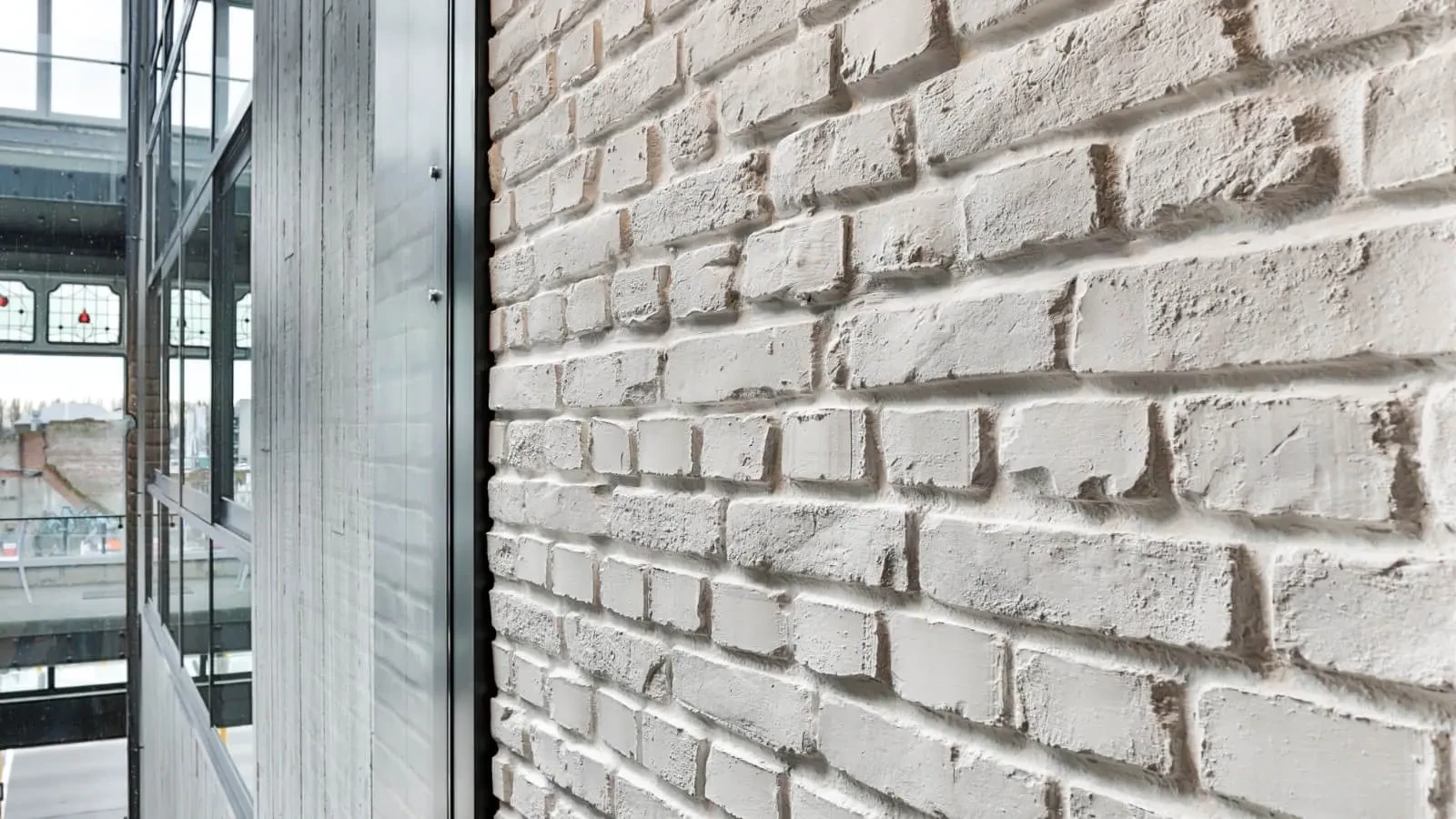 A close up of a white brick wall next to a window.