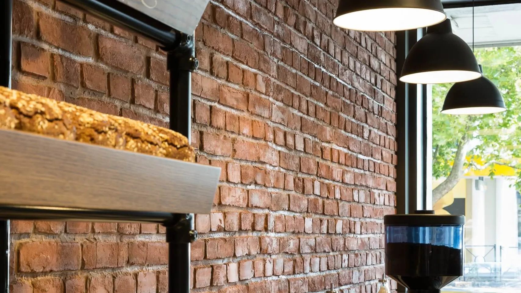 A bakery with a brick wall and a shelf with bread on it.