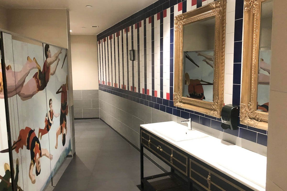 A long hallway with a painting on the wall and two mirrors.