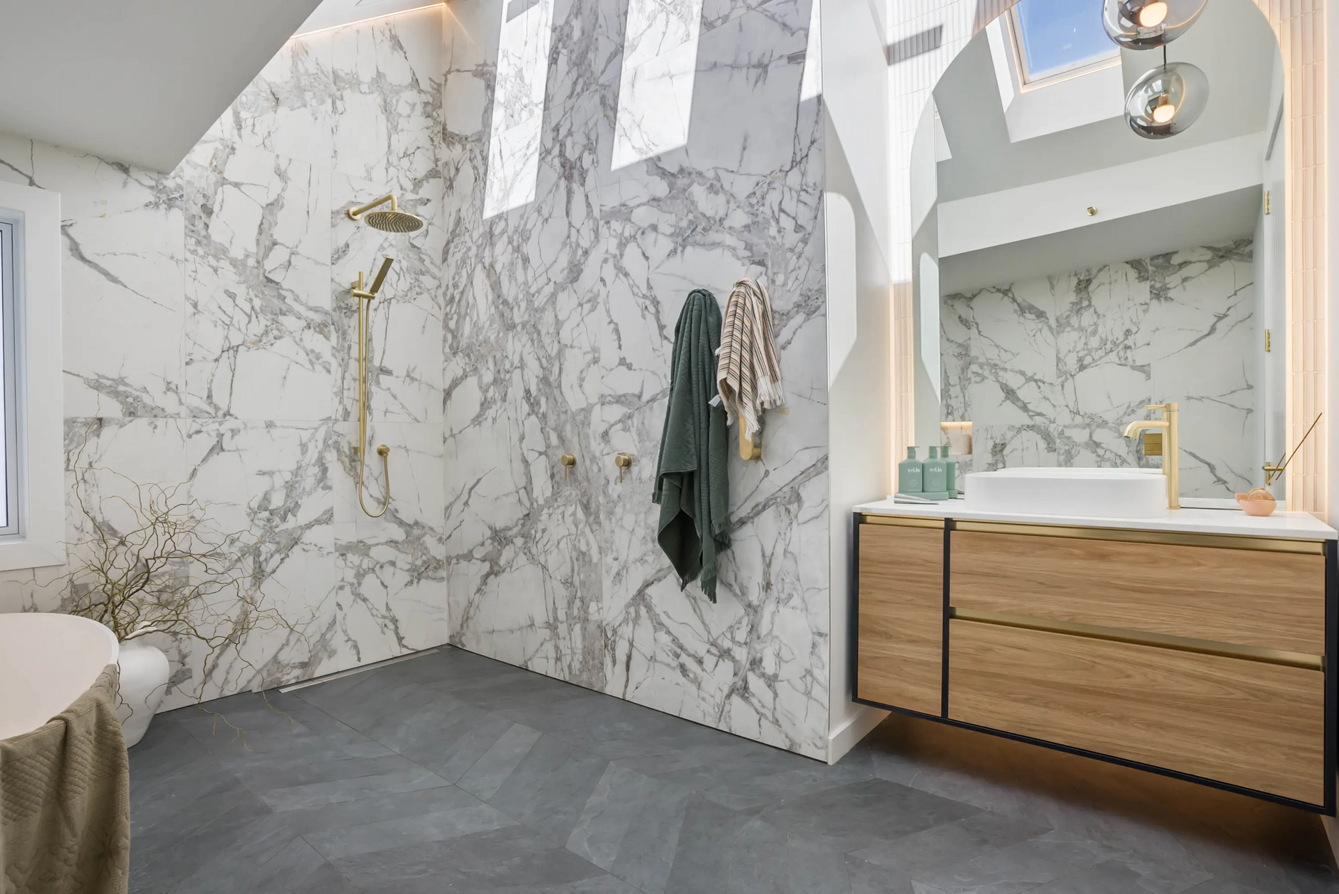 A bathroom with marble walls, a sink, and a shower.