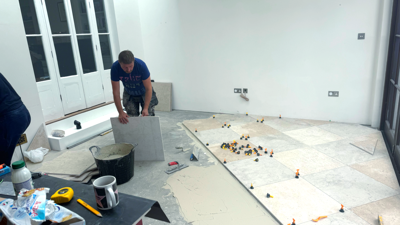 A man is working on a tile floor in a room.