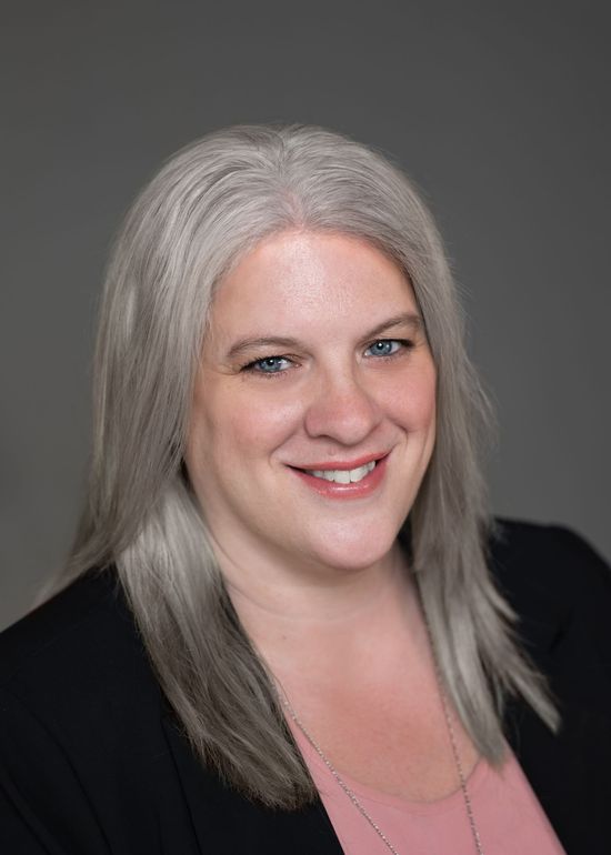 A woman with gray hair and blue eyes is smiling for the camera.