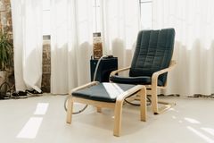 A chair and ottoman are in a living room next to a window.