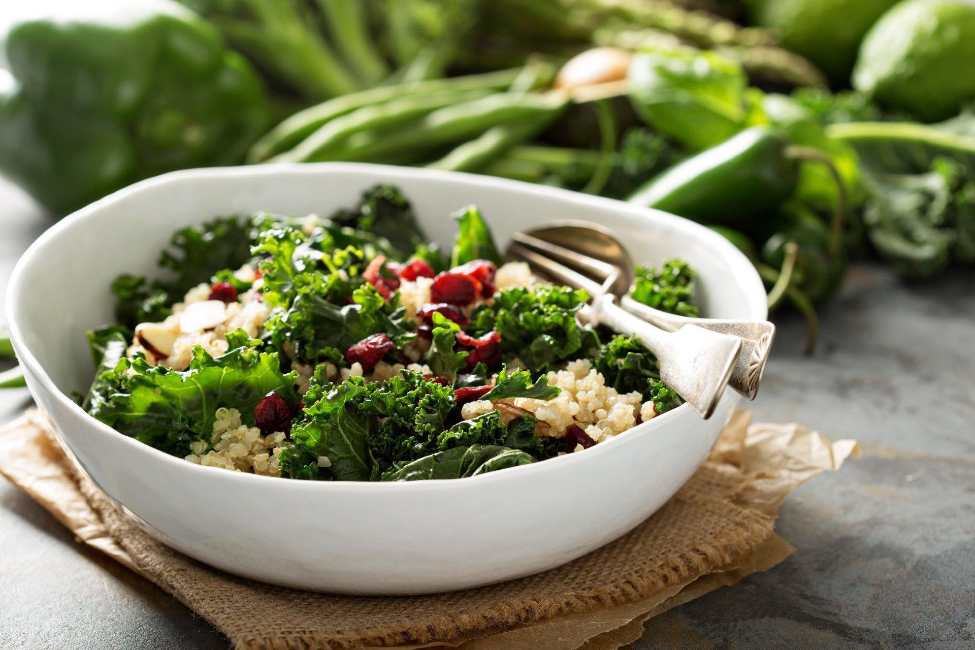 A bowl of kale and rice salad with a fork on a table.