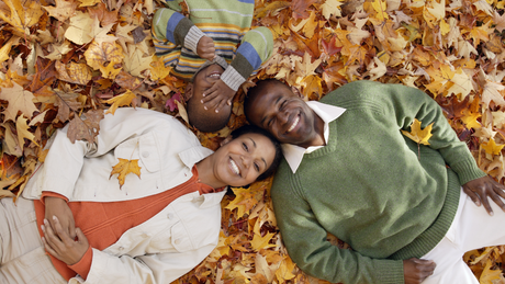 A family is laying in a pile of leaves.