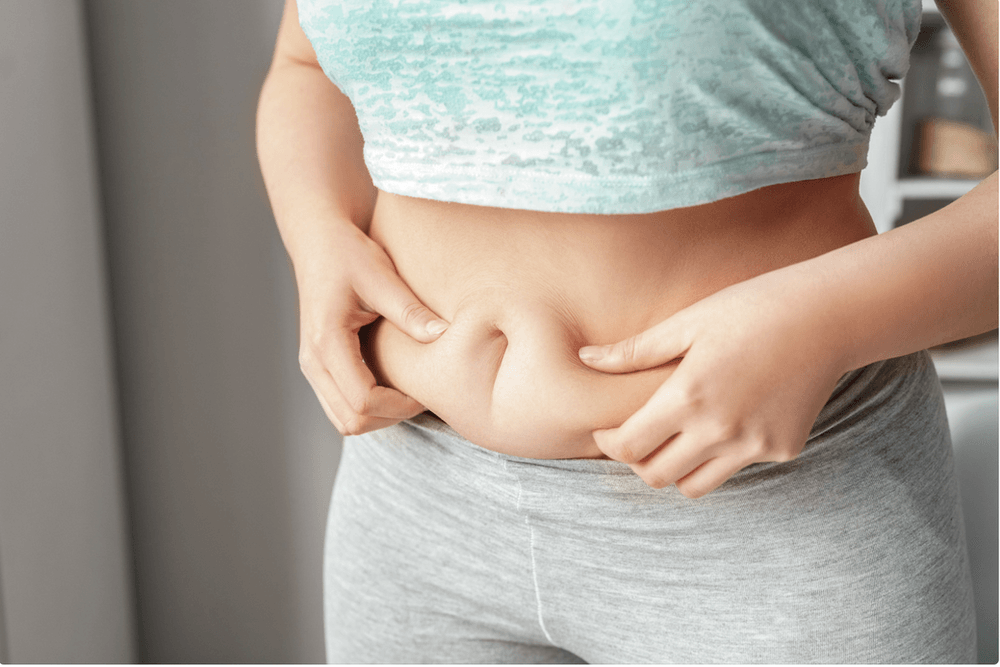 A woman is holding her belly with her hands.