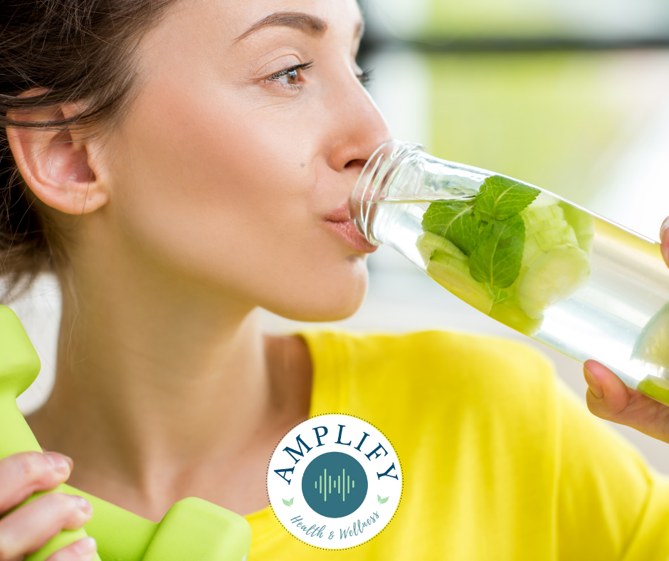 A woman is drinking water from a bottle with mint leaves.