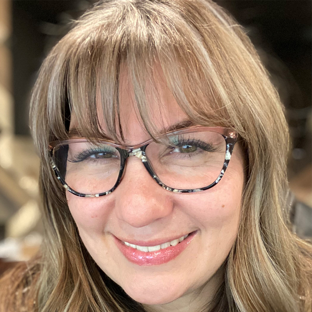 A close up of a woman wearing glasses and smiling.