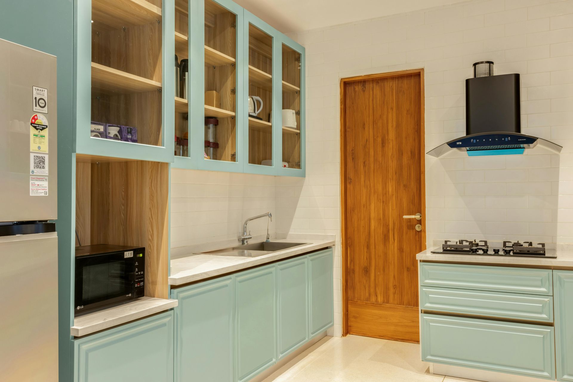 Light blue kitchen with wood-trimmed cabinets, stainless steel appliances, and a wooden door.