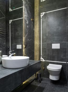 Bathroom with dark gray marble walls, white sink, and toilet.