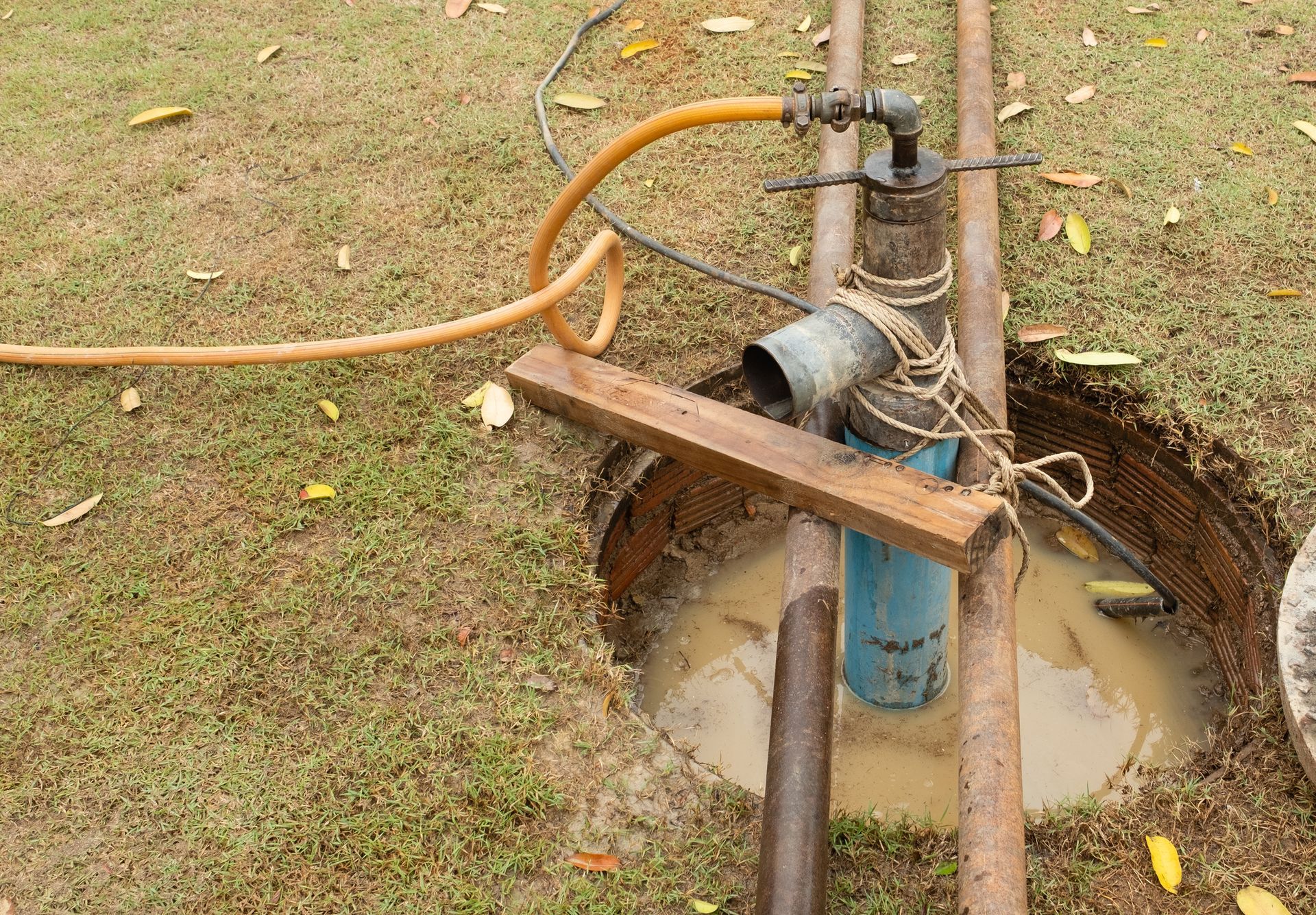 A water pump is being installed in a hole in the ground.
