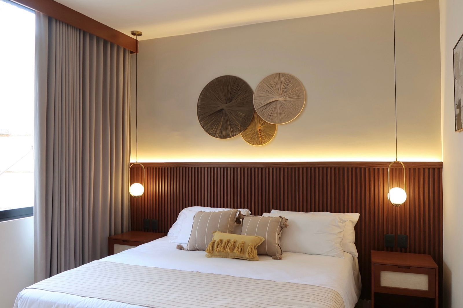 Bedroom with a wooden headboard, decorative wall art, and bedside tables. Beige, brown, and gold tones.