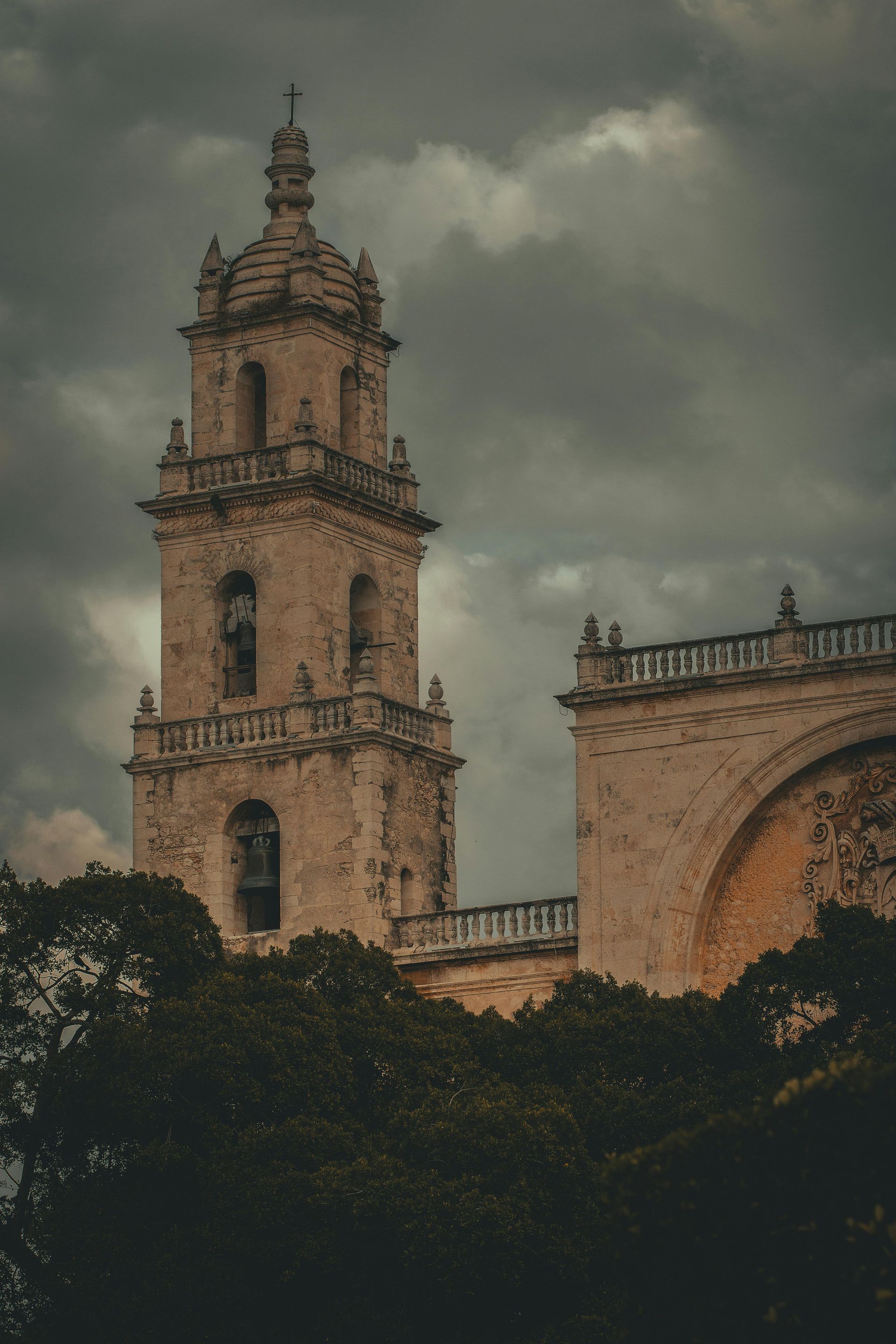 Stone church tower under a cloudy, overcast sky.