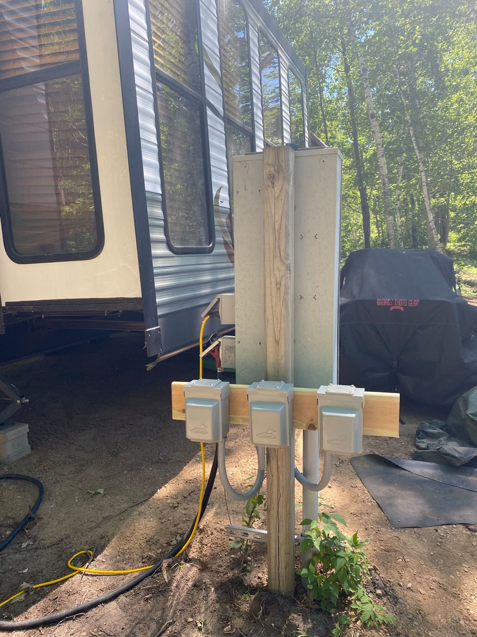 A rv is parked next to a wooden post with electrical outlets attached to it.