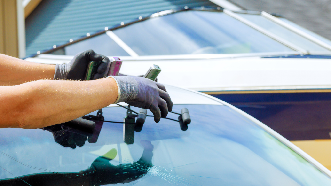 Person using tools to repair a cracked car windshield.
