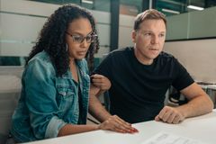 A man and a woman are sitting at a table looking at a piece of paper.