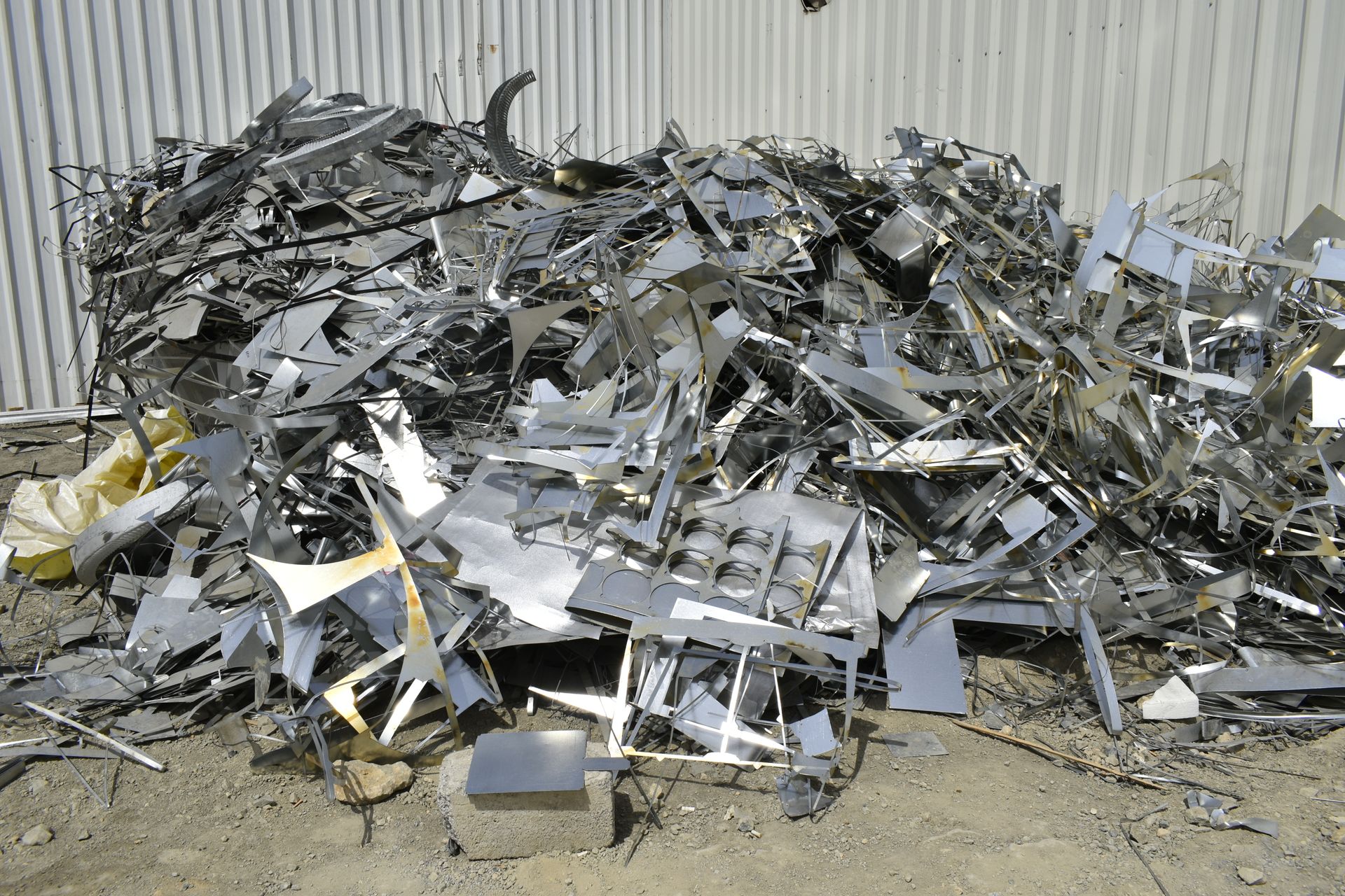 A pile of scrap metal is sitting on the ground in front of a building.