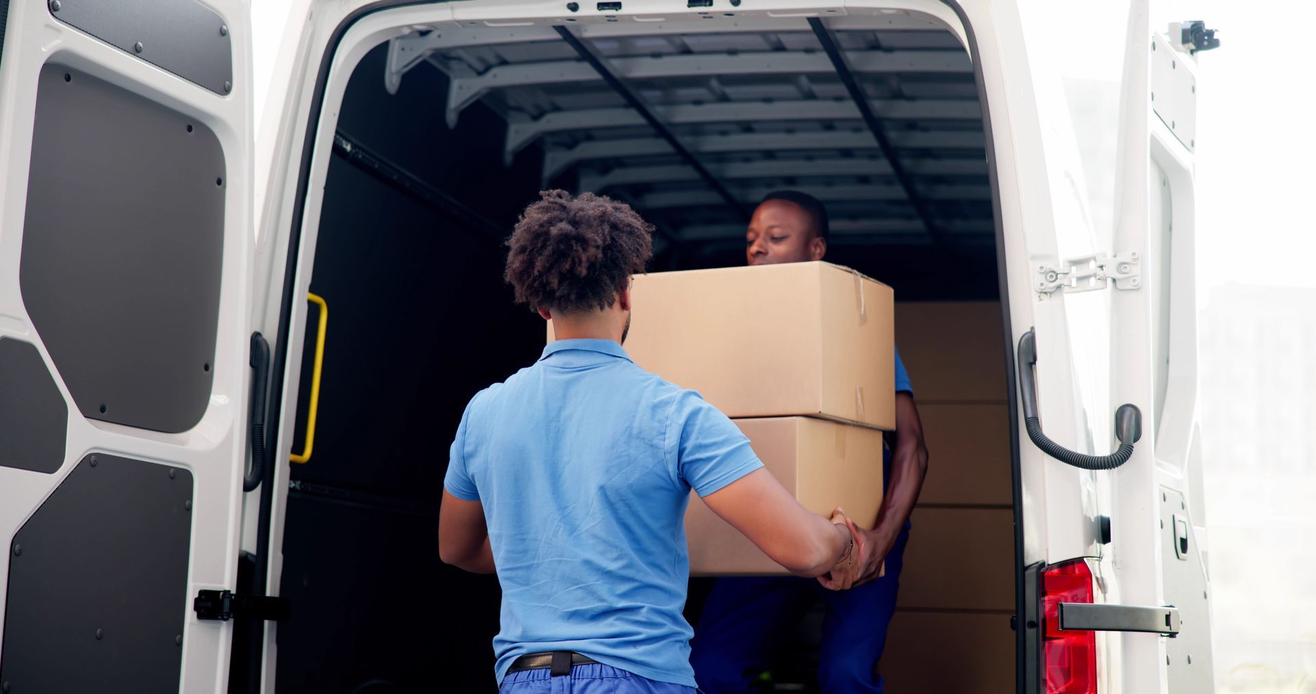 A man is loading boxes into a white van.