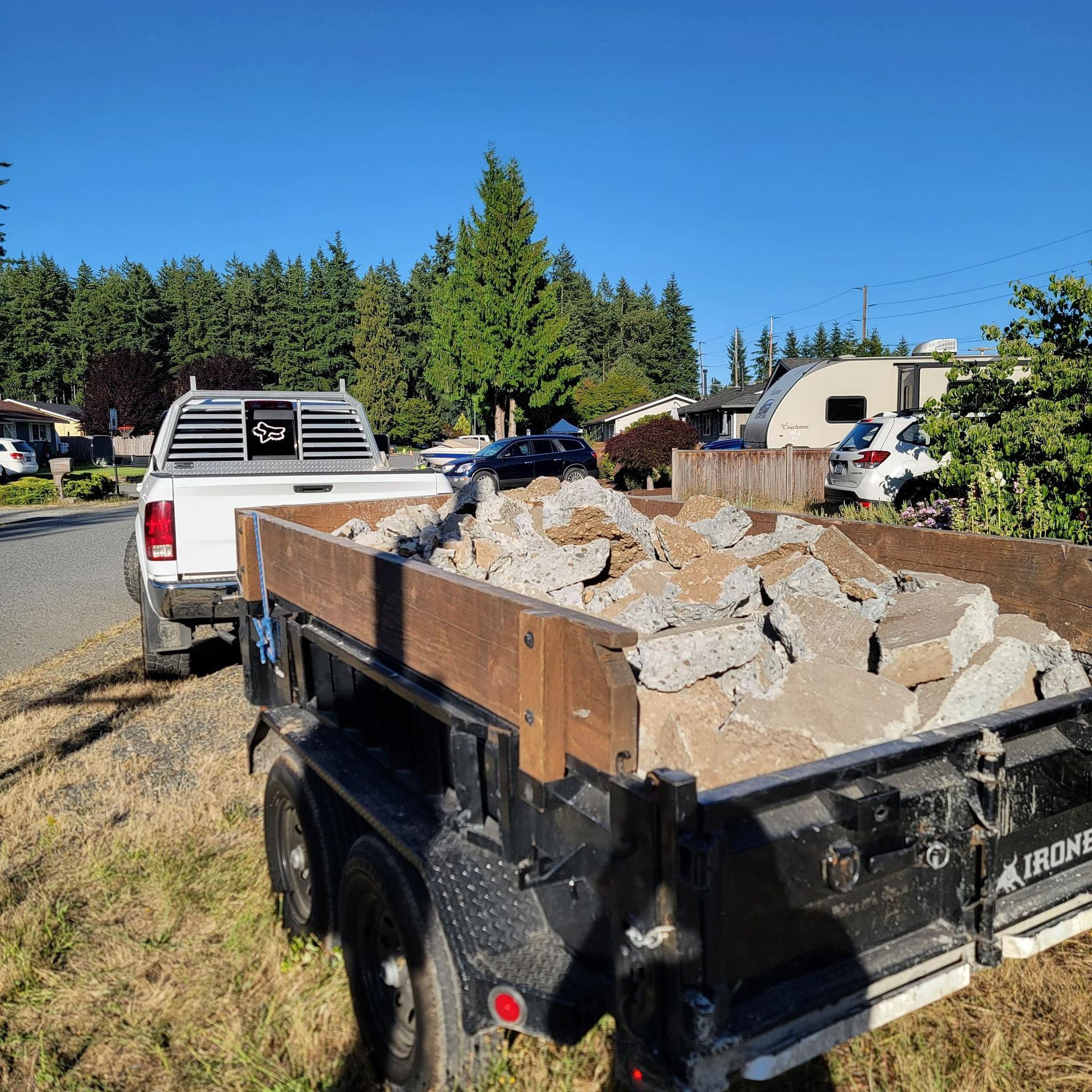 A truck is parked next to a trailer filled with rocks.