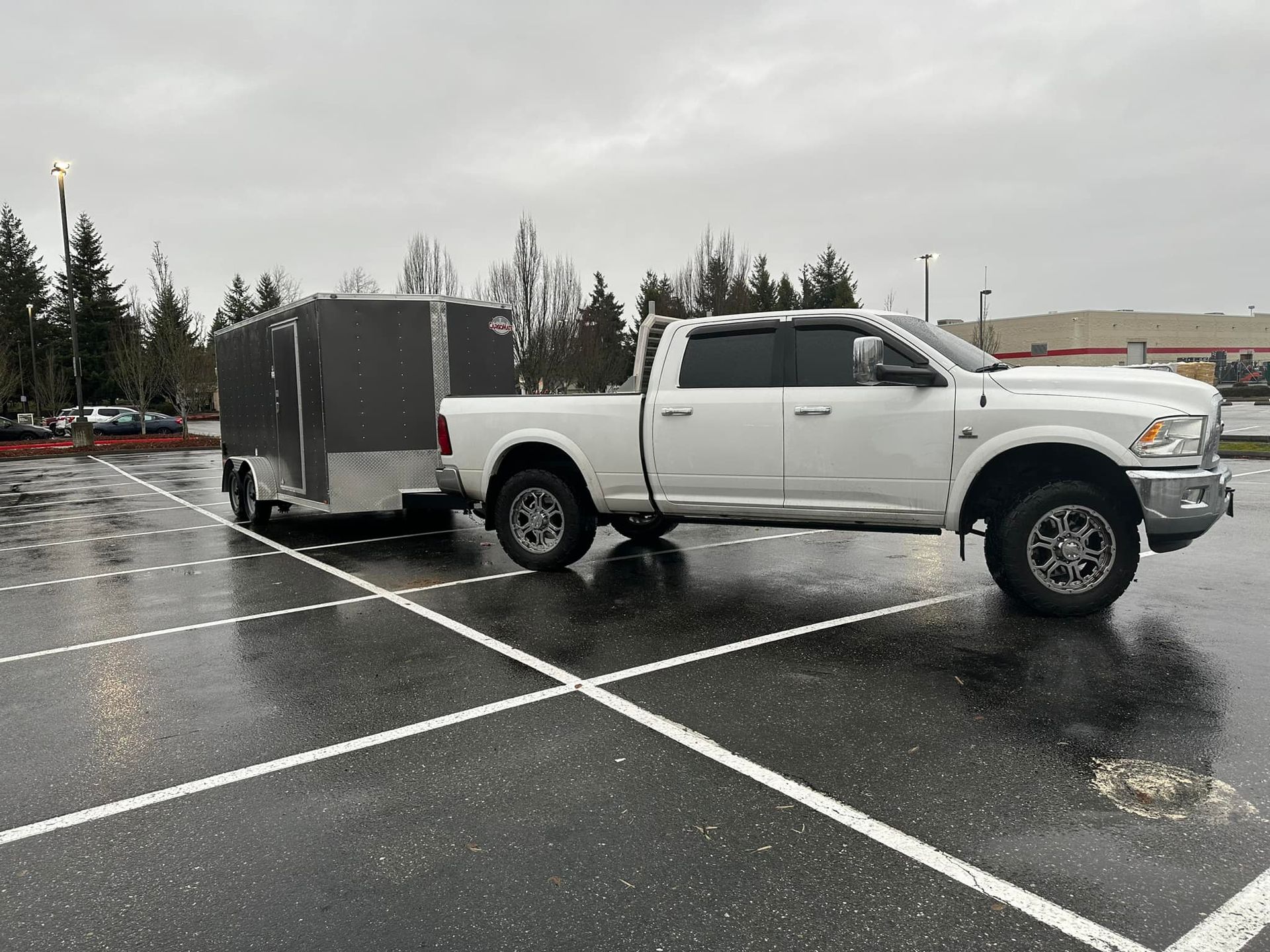 A white truck is pulling a trailer in a parking lot.