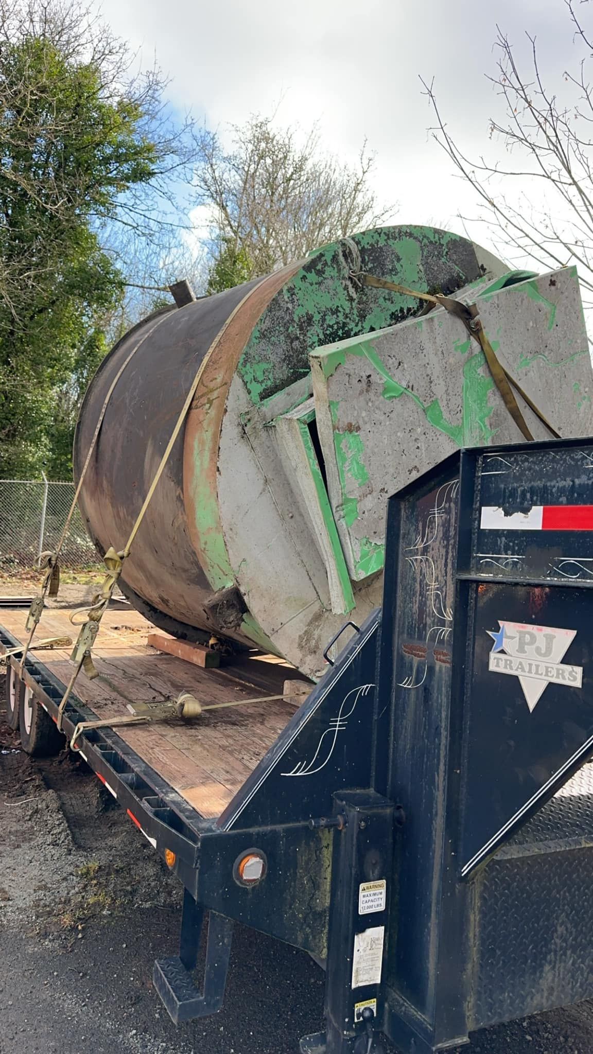 A large concrete mixer is sitting on top of a trailer.