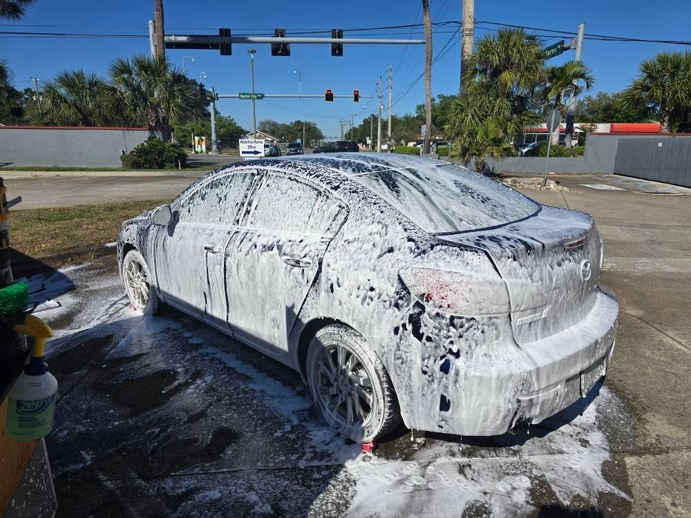 A car is covered in foam at a car wash.