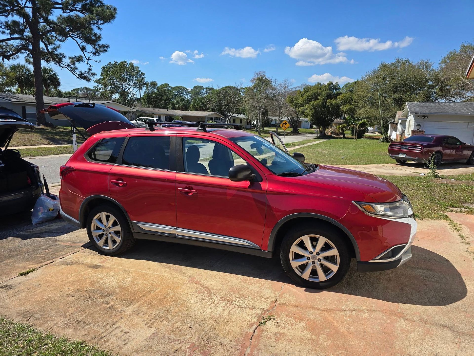 A red car is parked in a driveway in front of a house.